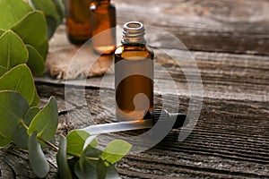 Bottle of eucalyptus essential oil on wooden background