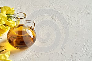 A bottle of evening primrose oil with fresh evening primrose flowers on white background