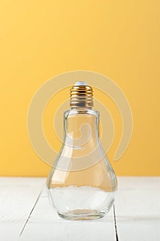 A bottle in the form of an incandescent lamp with a curved cover on a white-and-yellow background