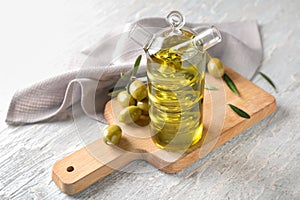 Bottle with fresh oil and canned olives on table