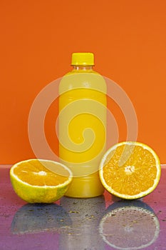 Bottle of fresh orange juice with fresh fruits on orange background