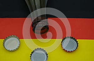 A bottle of German beer on top of a Germany flag,with three caps. Beer festival concept