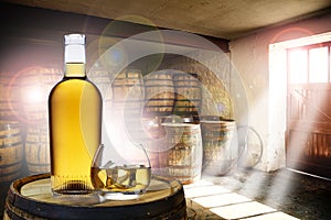 A bottle and glass of amber whisky set on top of an old barrel, in a barrel warehouse, with sun shining through the windows