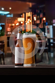 Bottle and glass of beer on counter in pub.