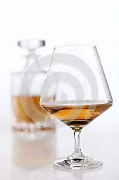 Bottle and glass of brandy on a white table