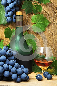 Bottle, glass of cognac and bunch of grapes