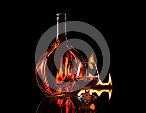 Bottle glass of cognac in fire flame