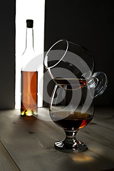 Bottle and glass of cognac over dark and white background