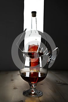 Bottle and glass of cognac over dark and white background