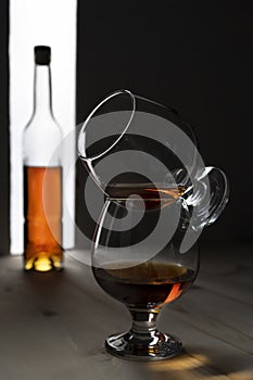 Bottle and glass of cognac over dark and white background