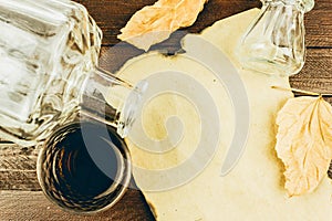 A bottle, a glass of cognac and a sheet of Kraft paper on a wooden table