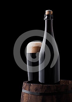 Bottle and glass of stout beer on wooden barrel