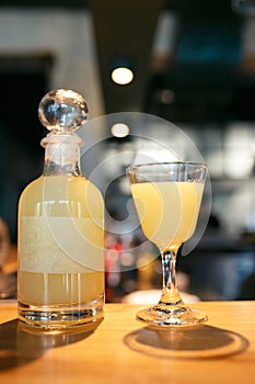 Bottle and glass filled with yellow alcoholic drink on the bar counter