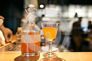 Bottle and glass filled with yellow alcoholic drink on the bar counter