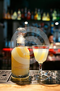 Bottle and glass filled with yellow alcoholic drink on the bar counter