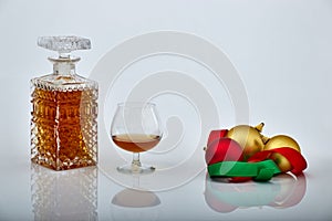 Bottle and glass of liquor with Christmas ornaments, white backgrounds and reflections