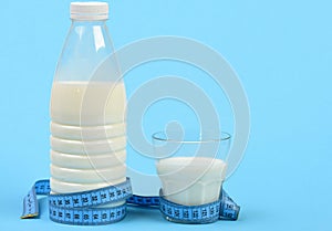 Bottle and glass of milk with blue measuring tape