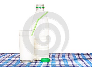 Bottle and glass of milk, on check tablecloth. Green straw.
