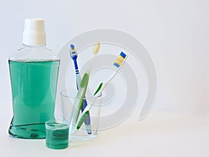 Bottle and glass of mouthwash on bath shelf with toothbrush. Dental oral hygiene concept. Set of oral care products photo