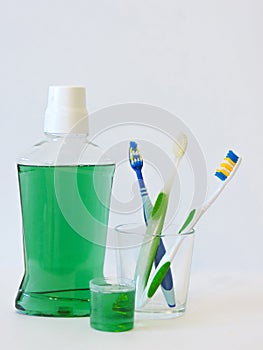 Bottle and glass of mouthwash on bath shelf with toothbrush. Dental oral hygiene concept. Set of oral care products