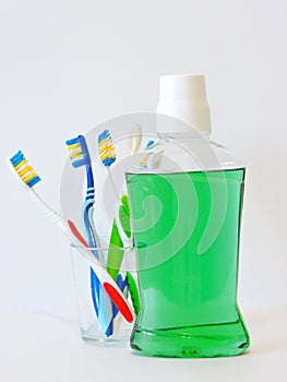 Bottle and glass of mouthwash on bath shelf with toothbrush. Dental oral hygiene concept. Set of oral care products