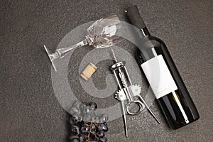 Bottle and glass of red wine with bunch of grapes,corkscrew, on black wooden table., top view