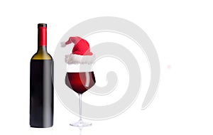 Bottle with glass with red wine in Christmas hat isolated on a white background