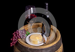 Bottle And Glass Of Red Wine With Grapes And Cheese On Barrel