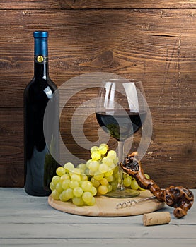 Bottle and glass of red wine, grapes and corkscrew made of vine