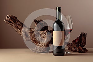 Bottle and glass of red wine with old weathered snag