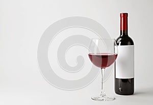 Bottle and glass with red wine on white background