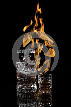 Bottle and glass of scotch on a dark background with flames