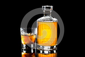 Bottle and a glass of whiskey on the rock against a dark background