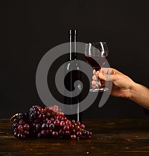 Bottle and glass of wine on dark brown background.