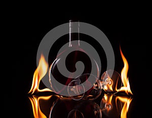 Bottle and glass of wine in fire flame