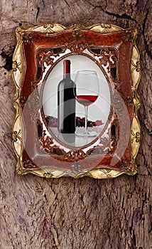 Bottle and glass wine in old picture frame on wood background