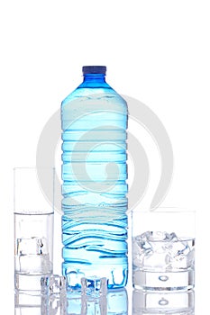 Bottle and glasses of mineral water with ice cubes