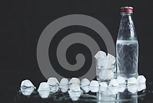 Bottle with glasses of vodka on black background