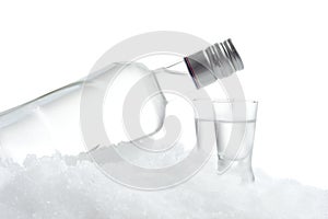 Bottle and glasses of vodka lying on ice on white background
