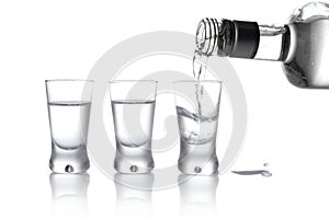 Bottle and glasses of vodka poured into a glass isolated on whit