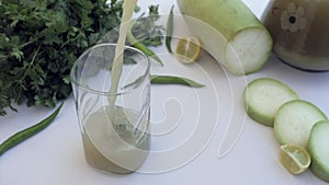 Bottle gourd drink with a slice of lemon is being poured in transparent glass - Giya juice