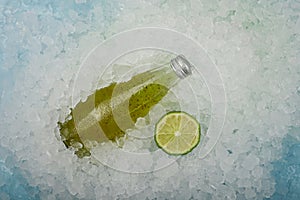 Bottle of green lime drink on crushed ice