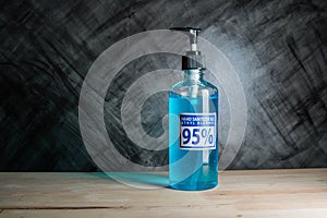 Bottle of hand sanitizer blue gel with ingredient ethyl alcohol 95% on wooden table with dark background