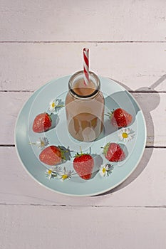 Bottle of healthy strawberry smoothie on the blue plate