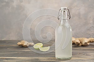 Bottle with homemade ginger ale, lemon and gingerroot on gray background. photo