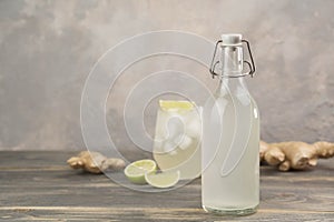 Bottle with homemade ginger ale, lemon and gingerroot on gray background. photo