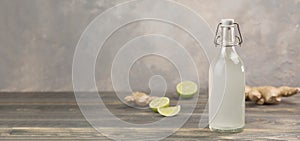 Bottle with homemade ginger ale, lemon and gingerroot on gray background. photo