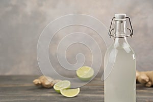 Bottle with homemade ginger ale, lemon and gingerroot on gray background. photo