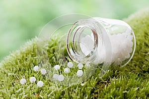 Bottle of homeopathy globules on moss. Selective focus.