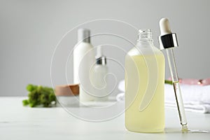 Bottle of hydrophilic oil and pipette on white table, space for text